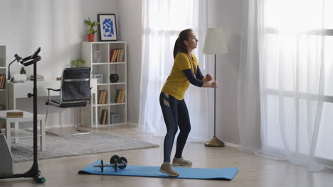 teenager-girl-is-training-alone-in-living-room-doing-aerobics-and-gymnastics-at-morning-keeping-fit-workout-and-sport-activity